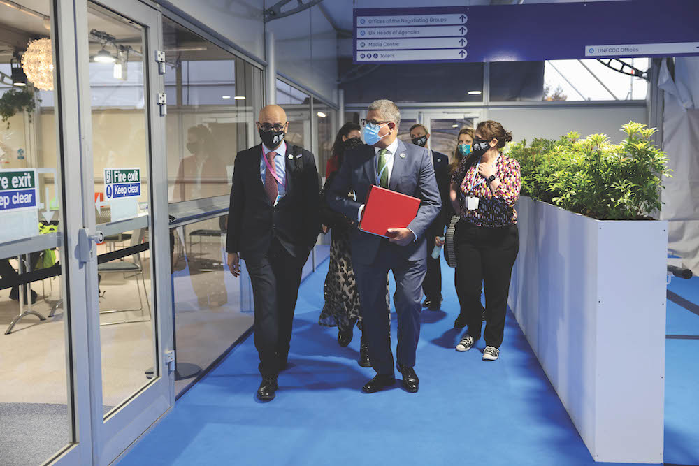 Wasim Mir and Alok Sharma, wearing masks, walk through the conference centre